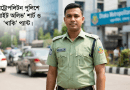 Bangladesh police officer in uniform standing on a city street with a Dhaka Metropolitan Police building in the background.